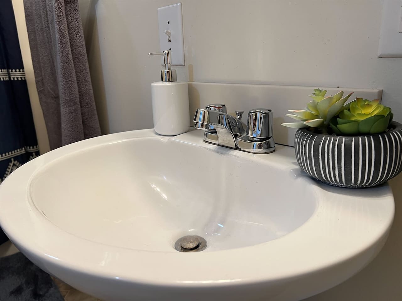 Modern full bathroom featuring a sleek sink with a stylish faucet and tasteful decorations—designed to offer a clean, functional space with a touch of elegance and contemporary charm