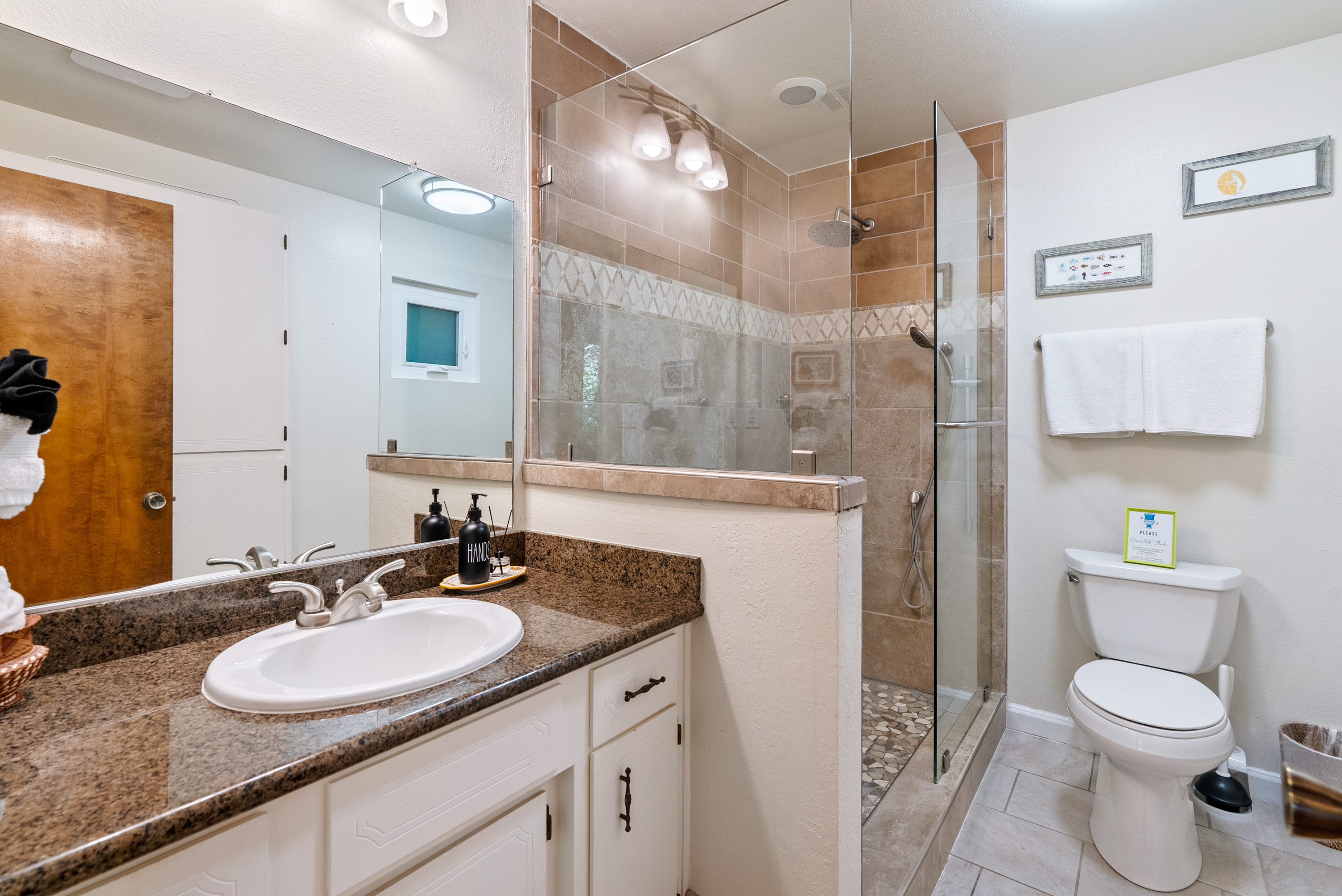 Bright, spacious bathroom with a modern walk-in shower and stone finishes.