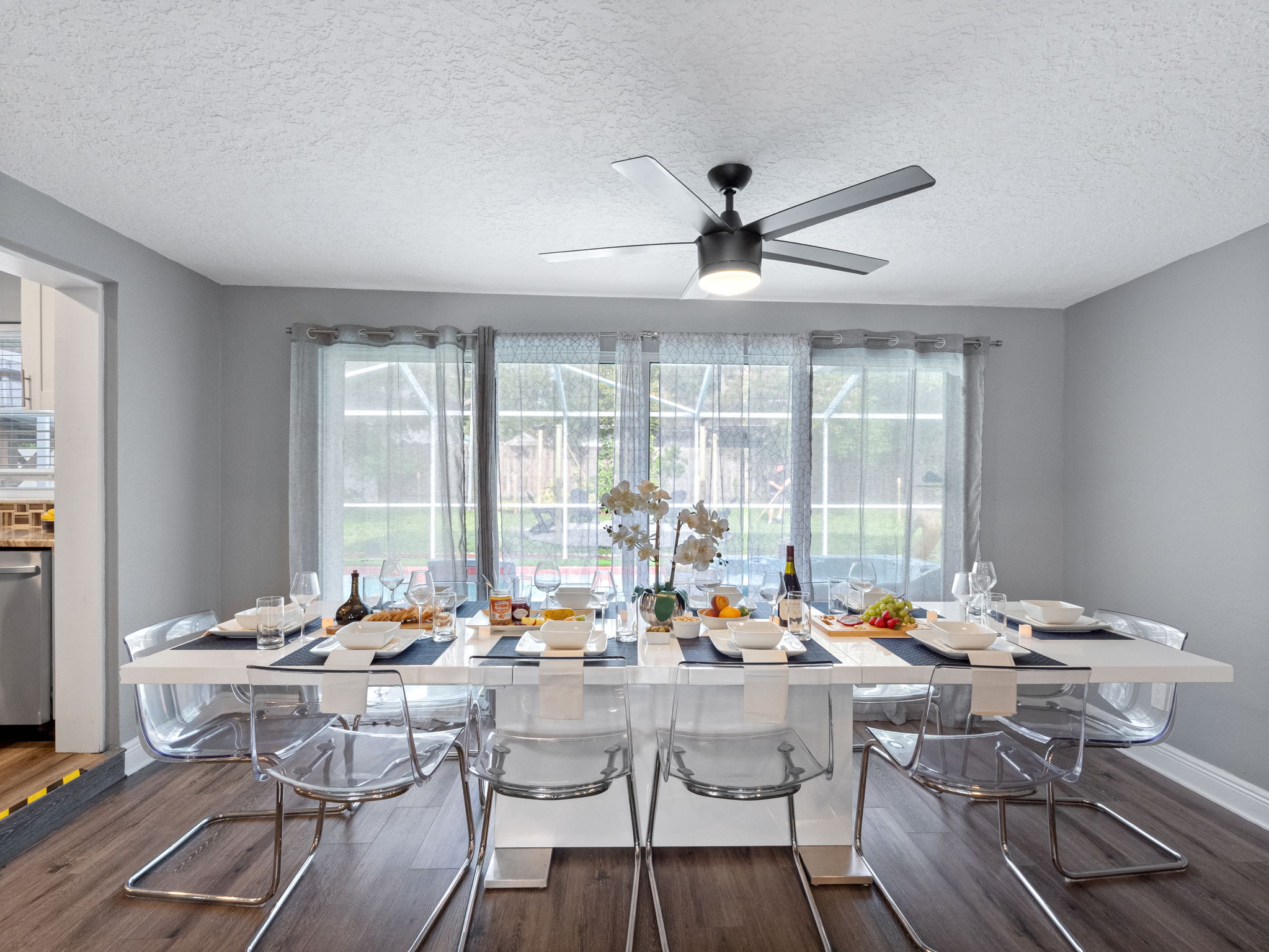 Surrounded by floor-to-ceiling windows with sheer curtains, this dining space is filled with natural light and peaceful views of the backyard.