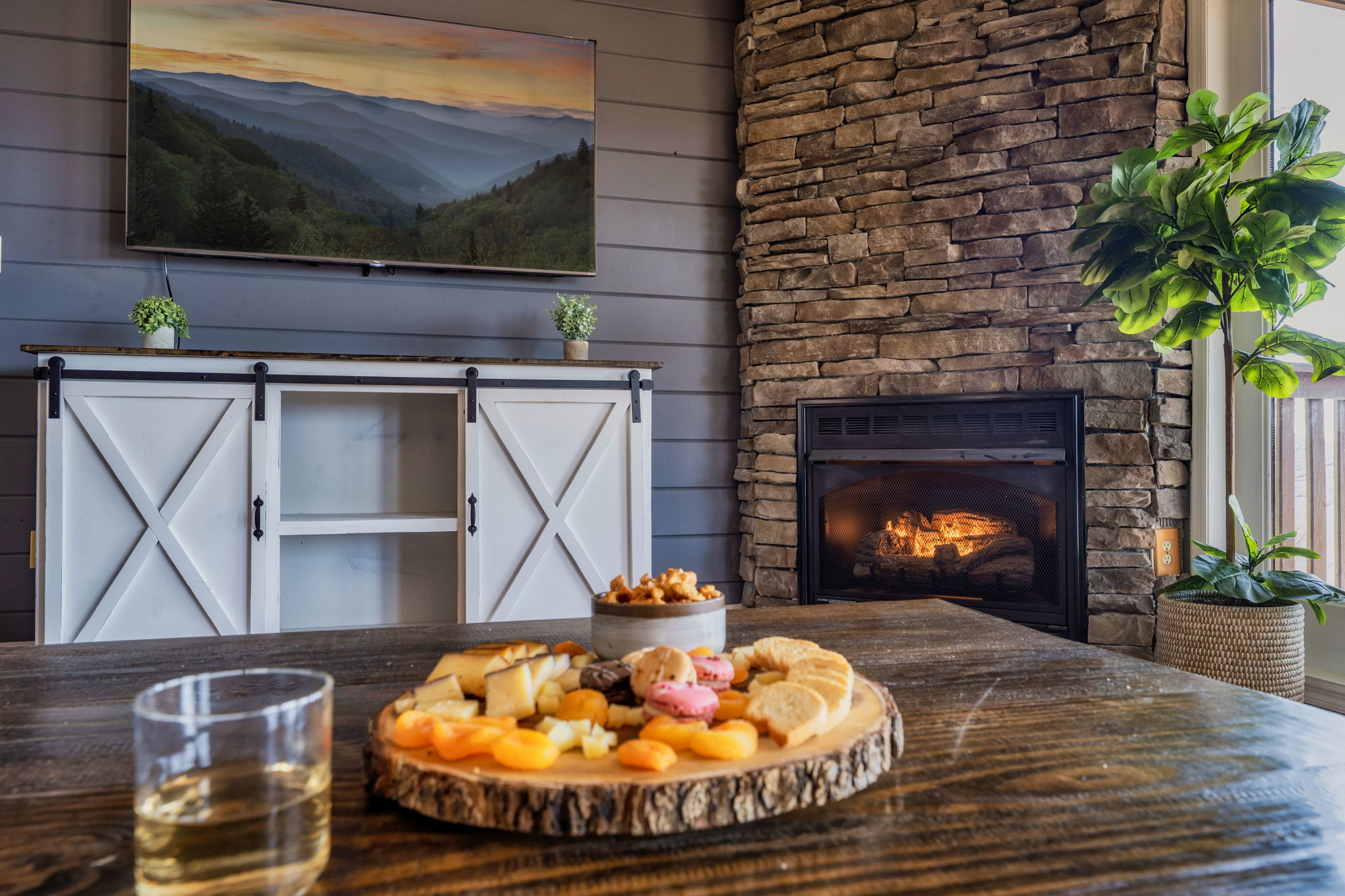 Settle into a spacious living room where breathtaking mountain views meet modern comfort and classic cabin charm - complete with a cozy fireplace, two oversized sofas, and a 65" Smart TV for relaxed evenings together.