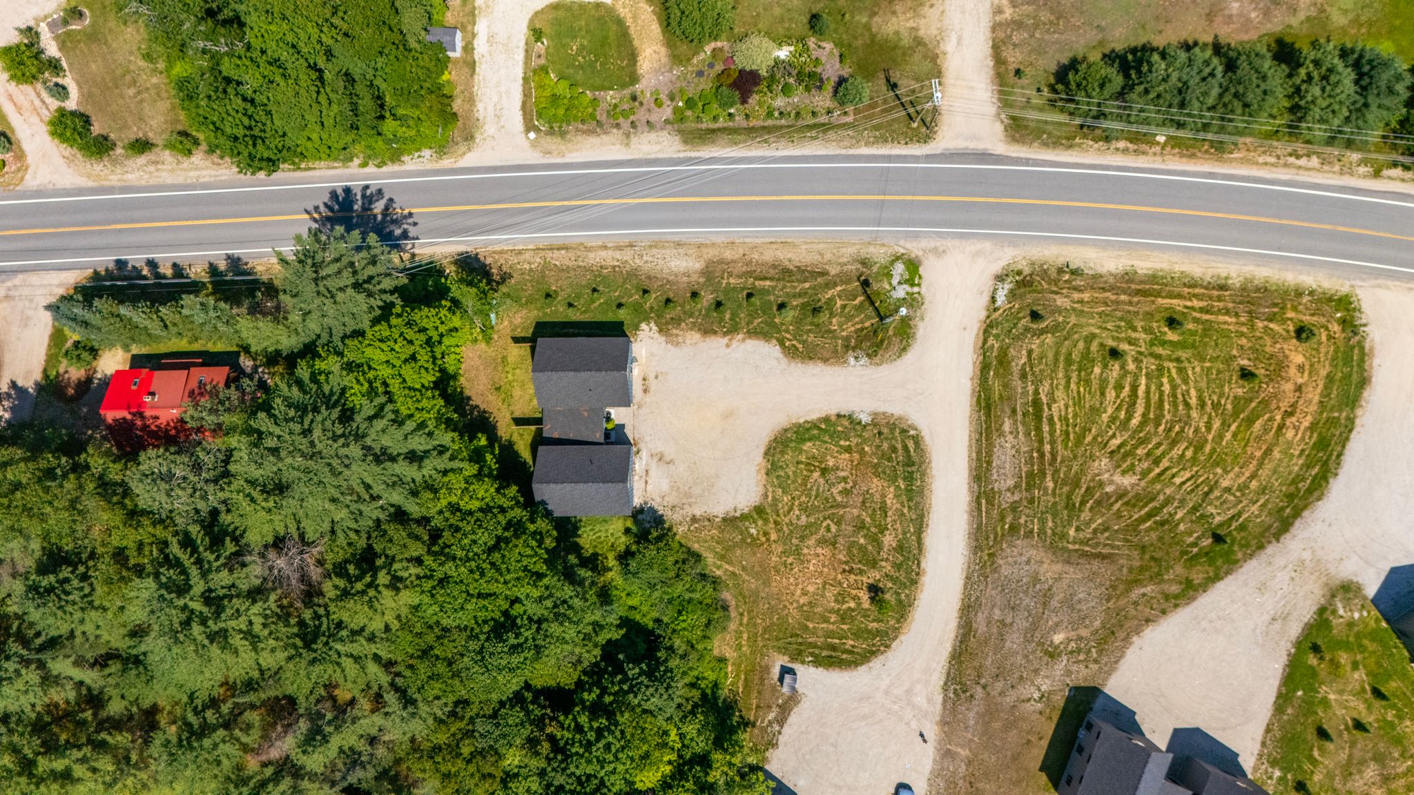 An aerial view highlights the property’s setting, convenient road access, and spacious parking area.