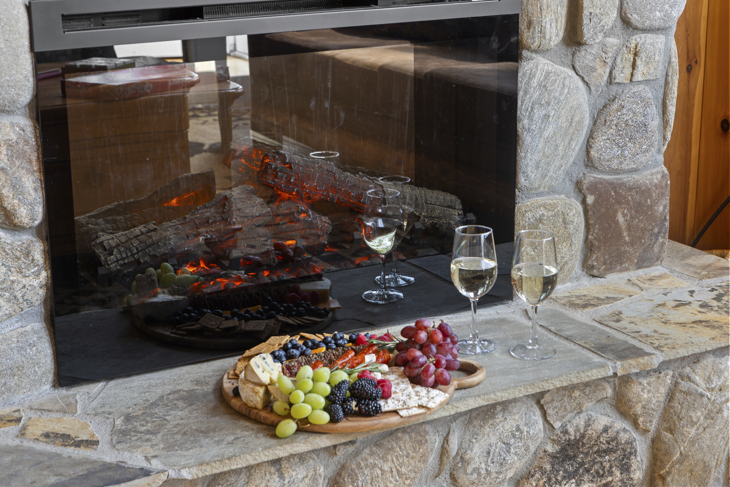 Living Area: Savor a gourmet cheese board by the fireplace with wine and stunning stone accents!