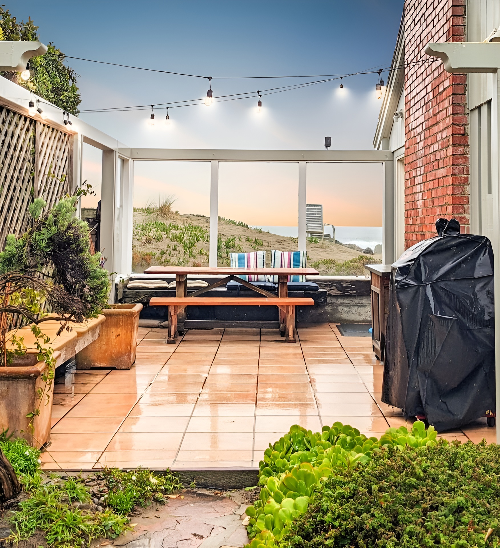 - Outdoor patio with picnic table, string lights, and views of the dunes  - Features BBQ grill for easy outdoor cooking and dining experiences  - Enclosed design offers a cozy gathering space in all seasons