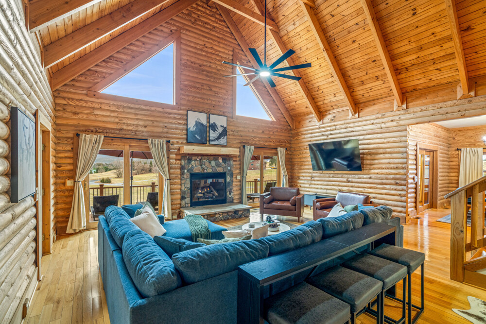 Spacious and inviting living area with a stone fireplace and large windows that bring in natural light and scenic views all day long.