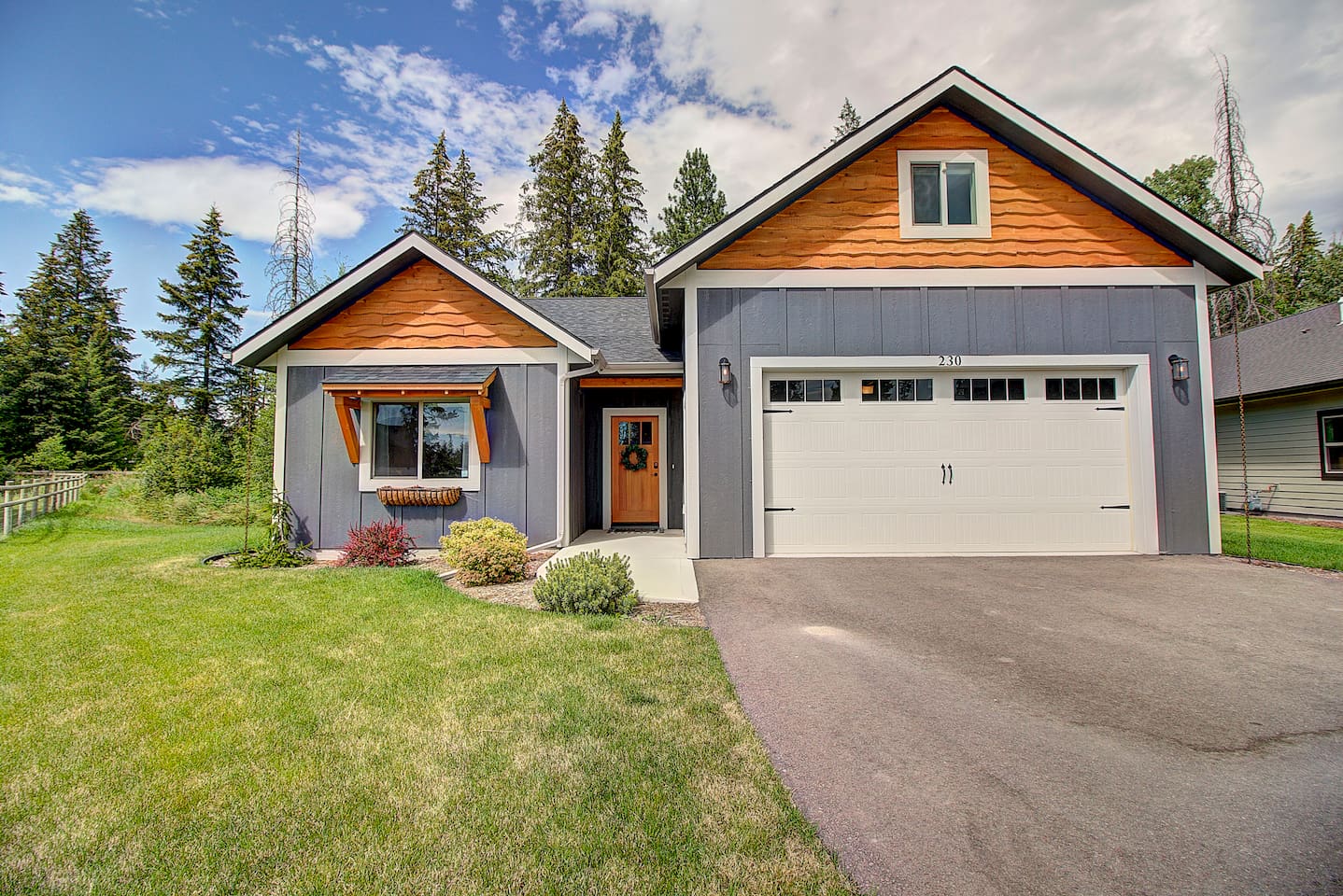 Gray and cedar come together beautifully here, with pines in the background and a spacious garage ready for your arrival.