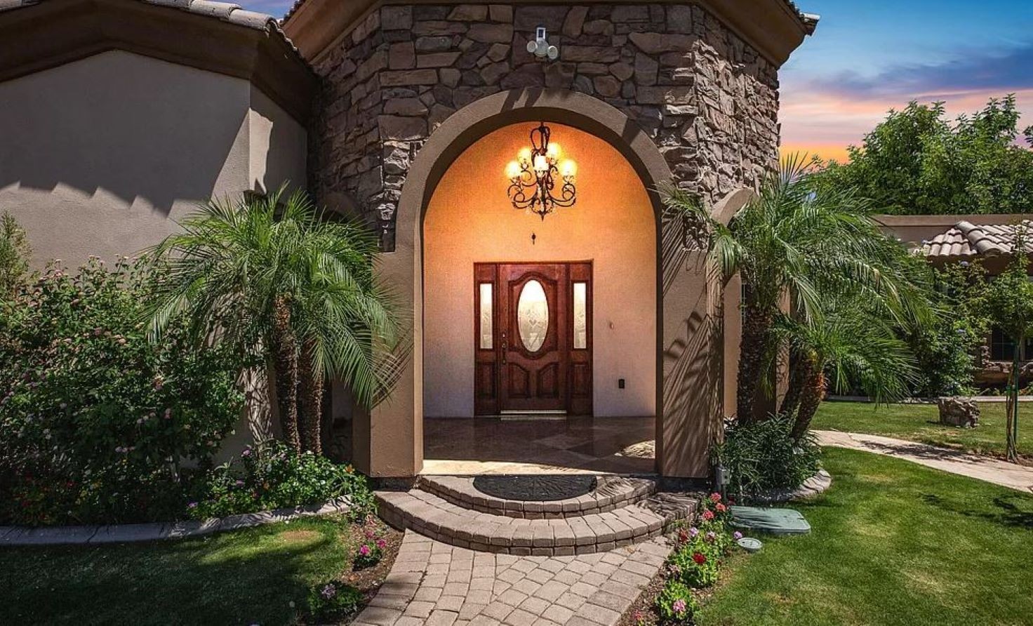 Make a grand entrance into your serene retreat, where lush landscaping, elegant stonework, and warm lighting set the tone for a relaxing stay.