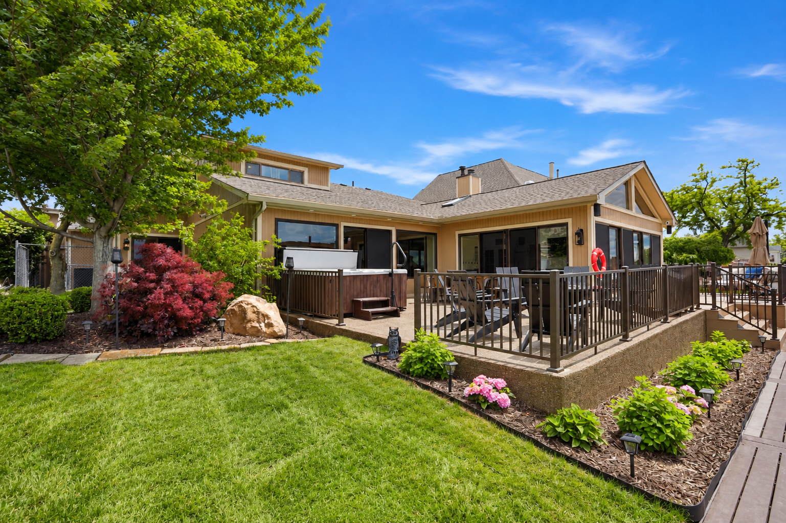 Spacious backyard patio with a hot tub, outdoor seating, and well-maintained landscaping. Private and relaxing outdoor space perfect for entertaining, unwinding, and enjoying warm-weather stays.