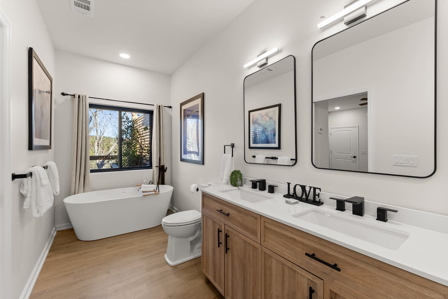 Master bathroom featuring a shower, double sinks, and a soaking tub with an outdoor view.