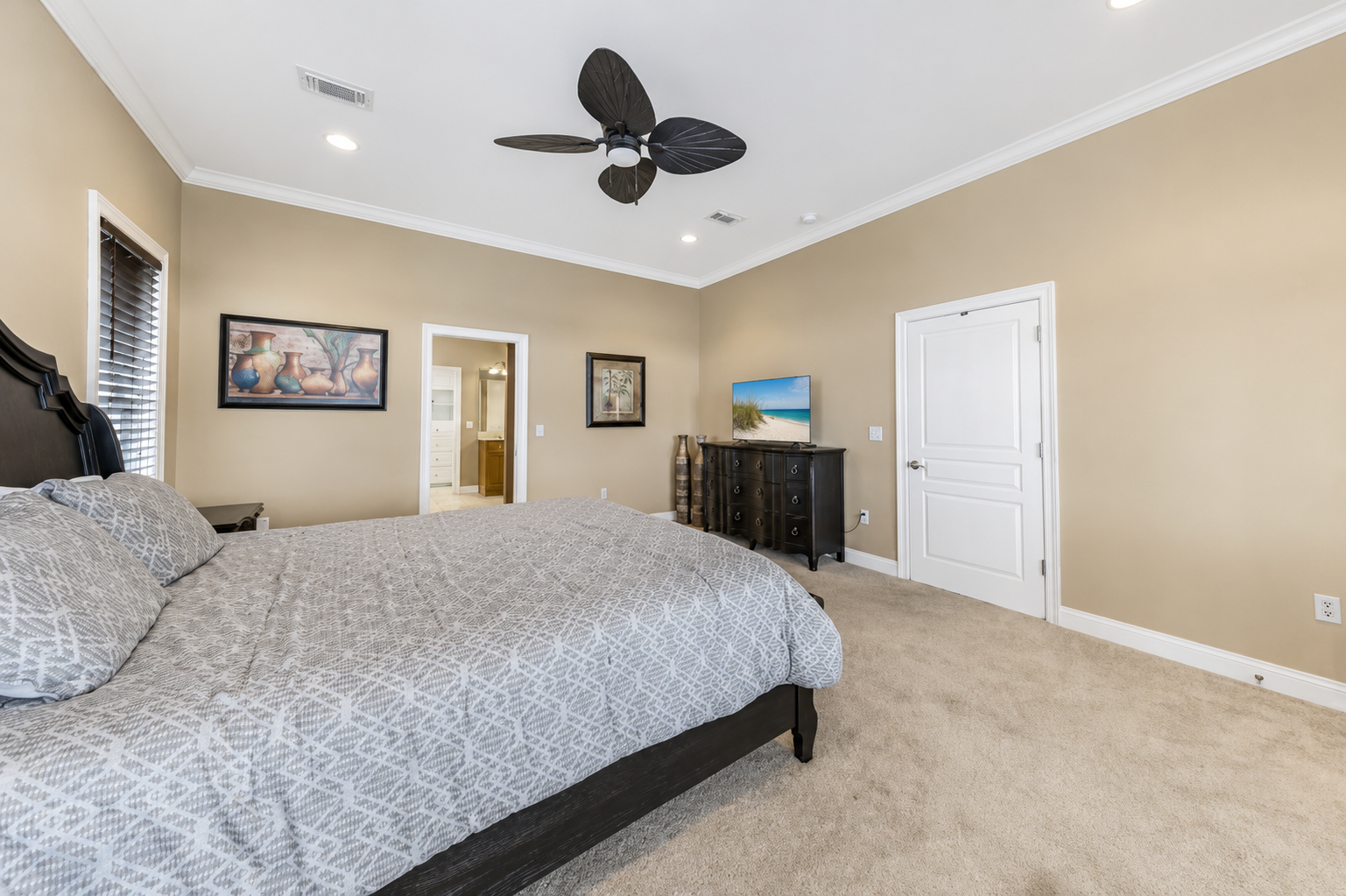 Guest bedroom with patterned bedding, ceiling fan, and a neutral coastal palette