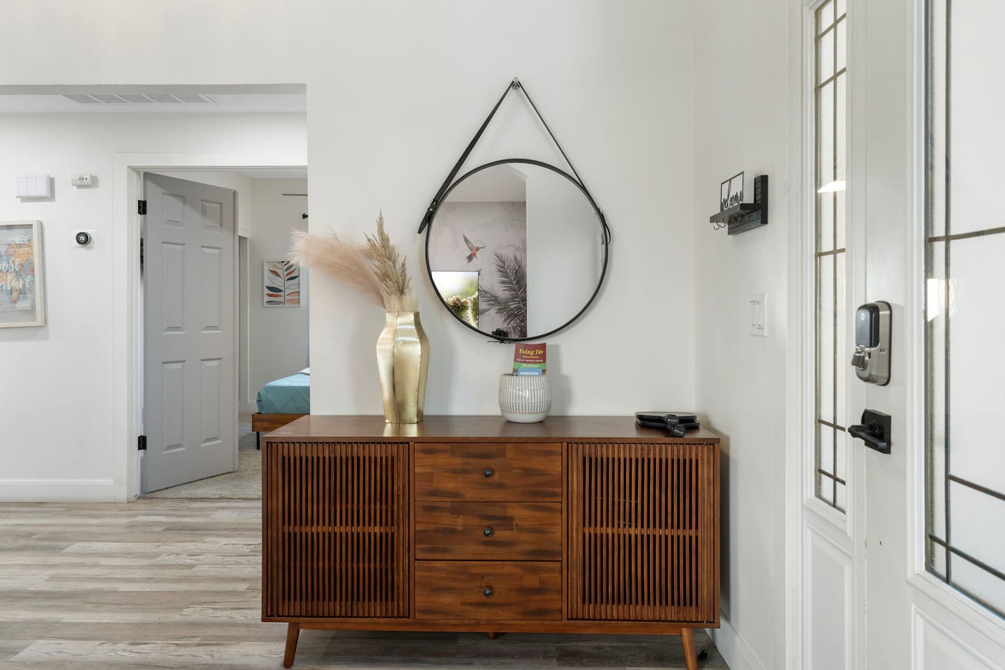 Bright, open entryway with designer mid-century console, statement mirror, and clean modern aesthetic.