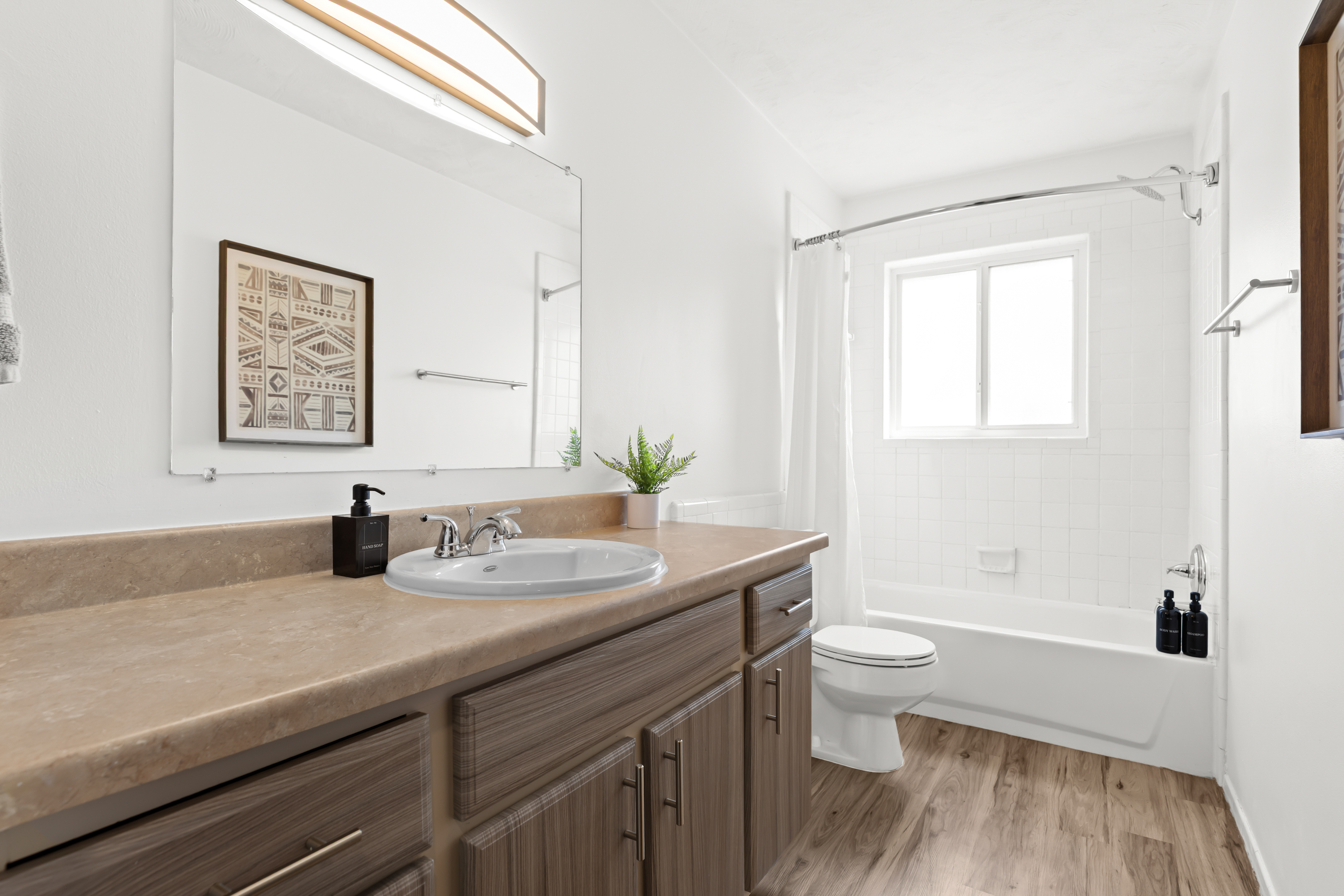 Refresh in a sleek, modern bathroom with crisp white tile, granite countertops, and a full-size tub/shower combo.