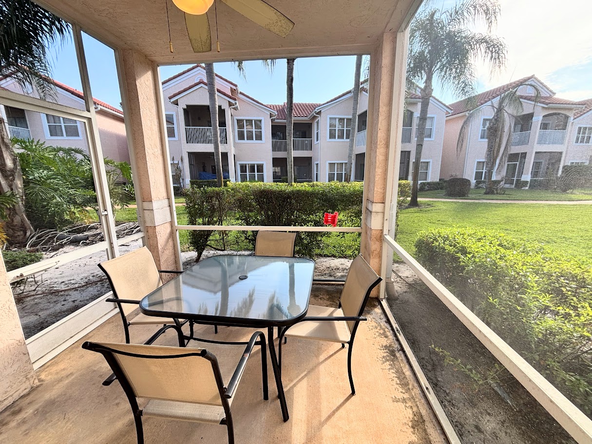 Private screened patio with outdoor dining space and peaceful views of the surrounding community grounds.