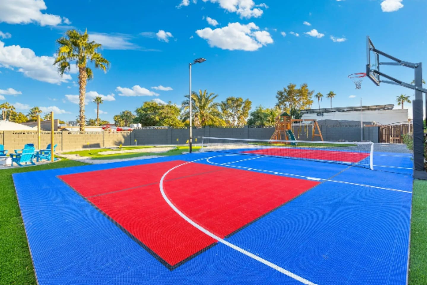 Bold color-blocked courts stretch across the yard, with the playground and pool area visible just past the fence line.