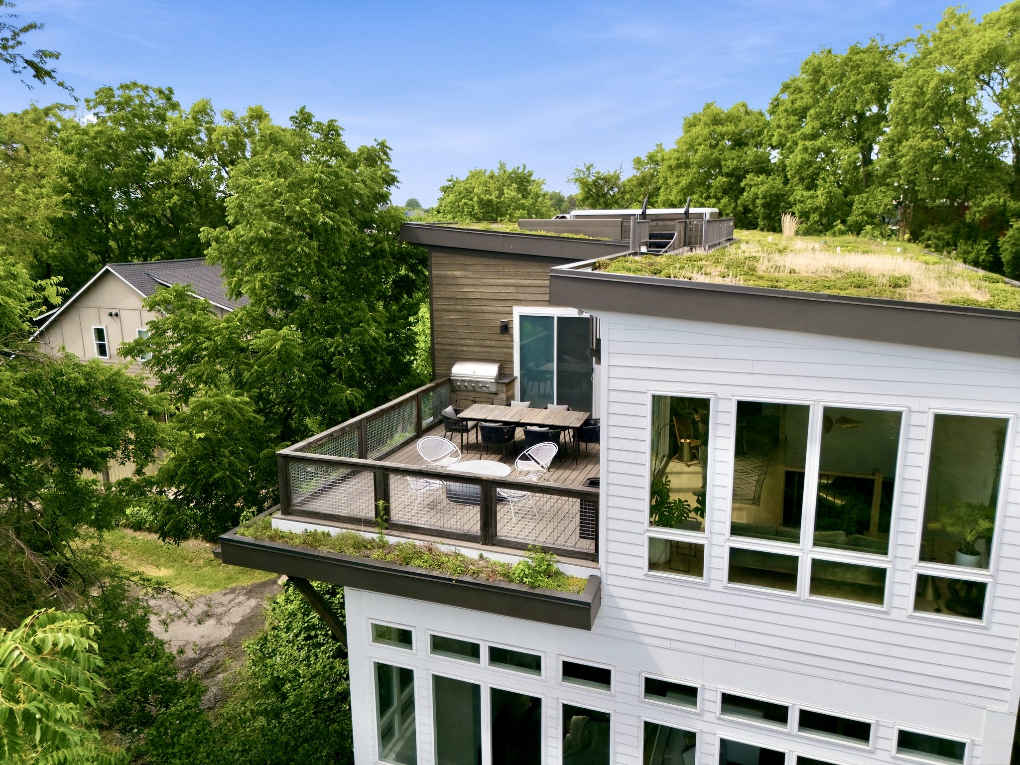 Rooftop terrace w/ lounge seating, green roof & panoramic treetop & skyline views all around.