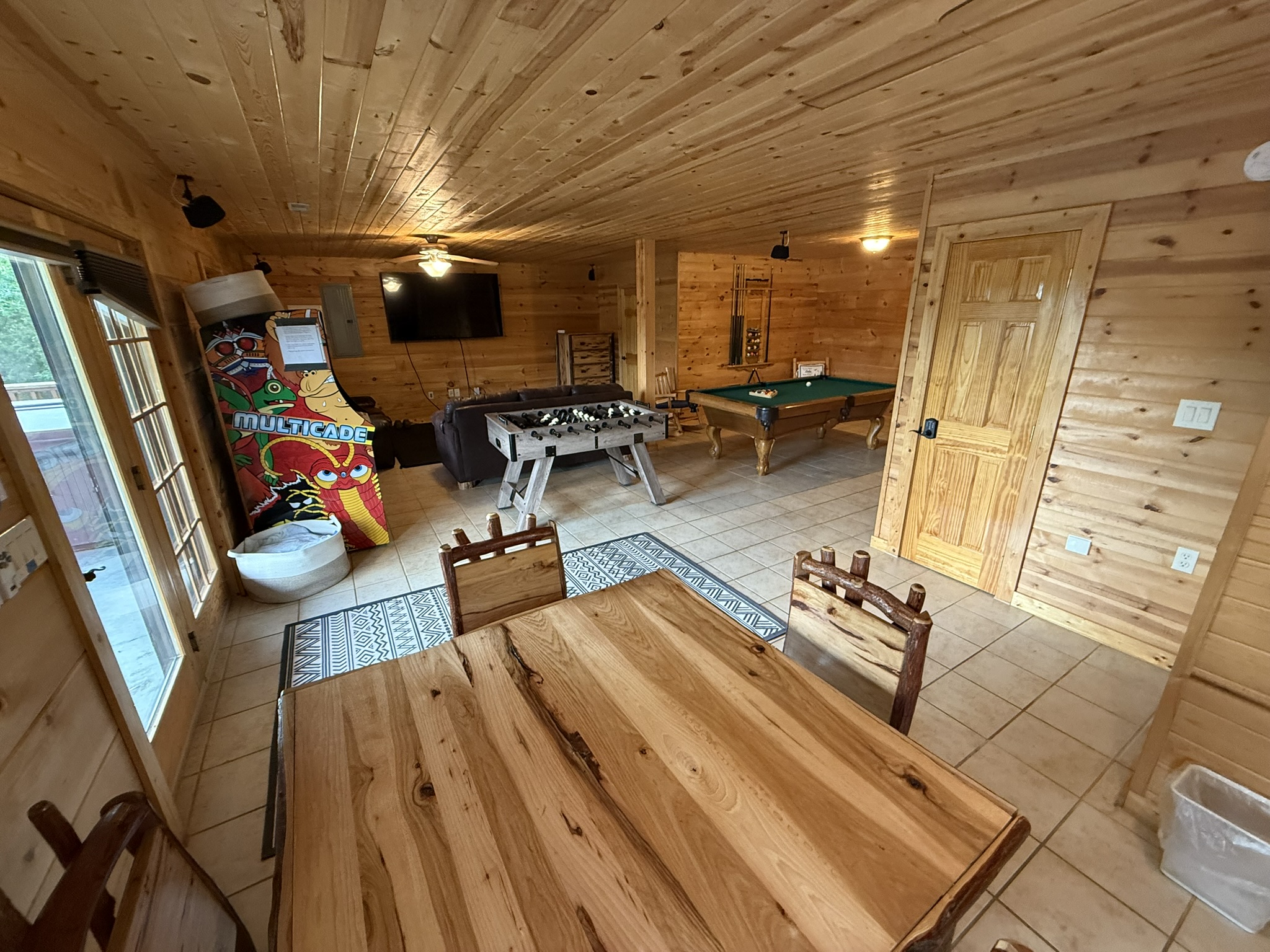 Game Room from a different angle in back where see Game Table, Large Screen TV, Foosball, Pool Table, Arcade games