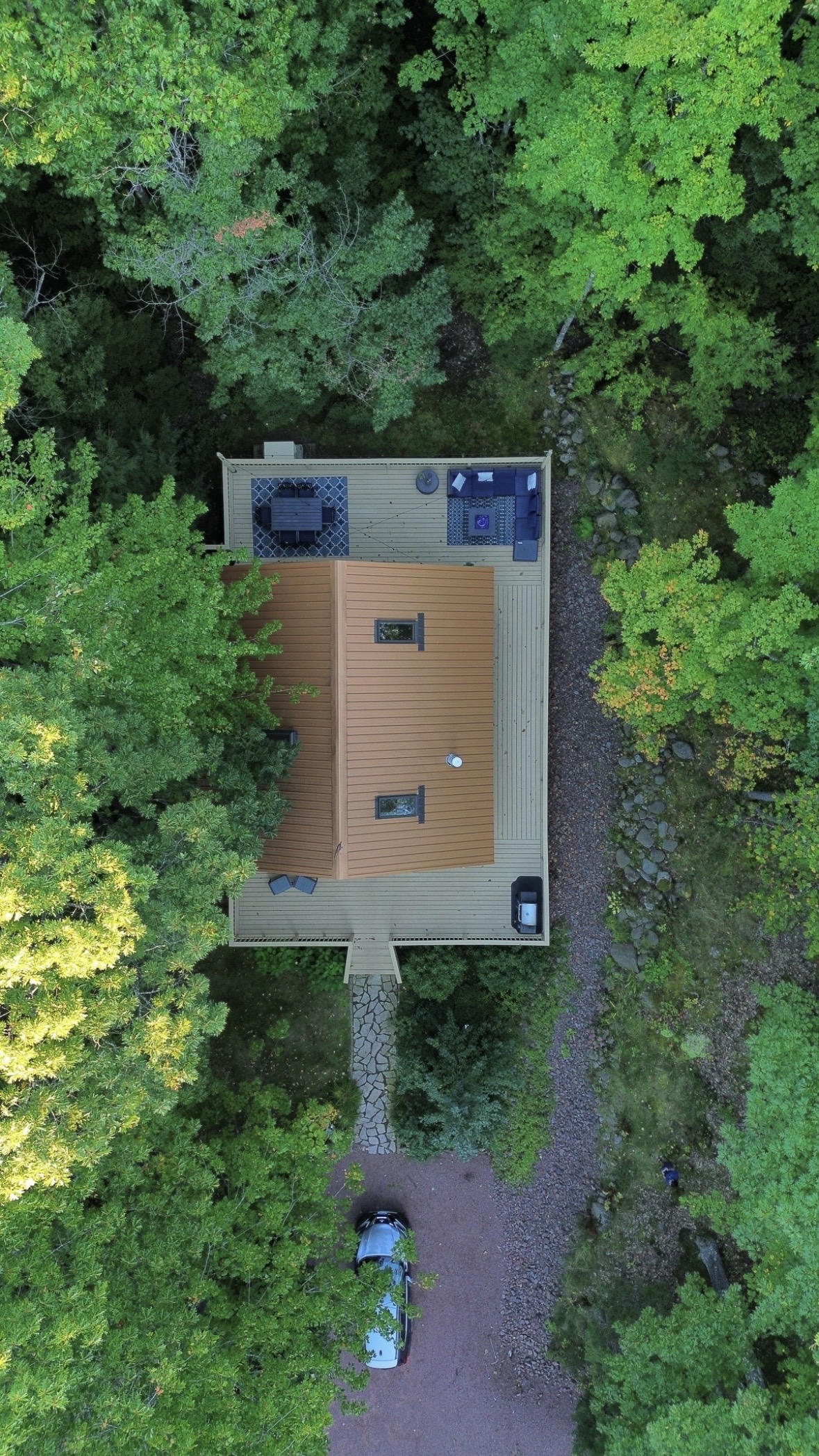 Drone aerial view of 1k wrap around deck, grill, back deck outdoor dining table, lounge couch, propane fireplace. 