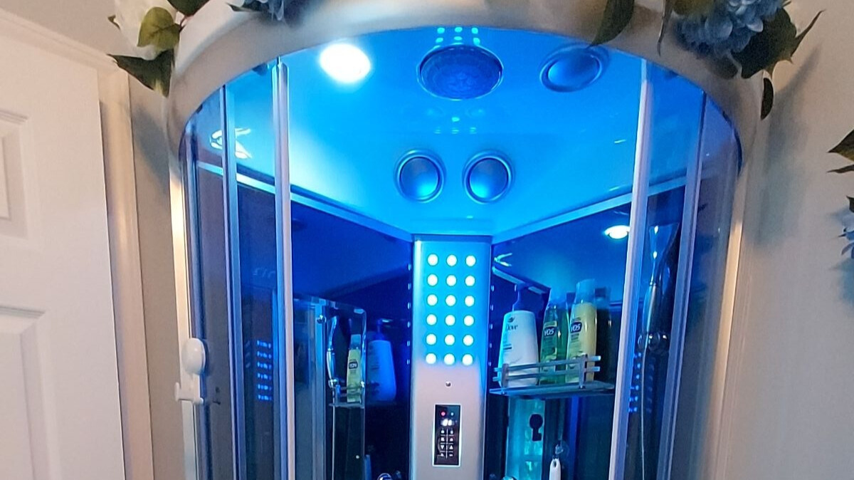 Step into your private spa unit, complete with a steam sauna and rainfall shower. Soft blue lighting sets a tranquil mood, and a built-in bench invites you to unwind. Just outside, a robe hook keeps towels or robes within reach.