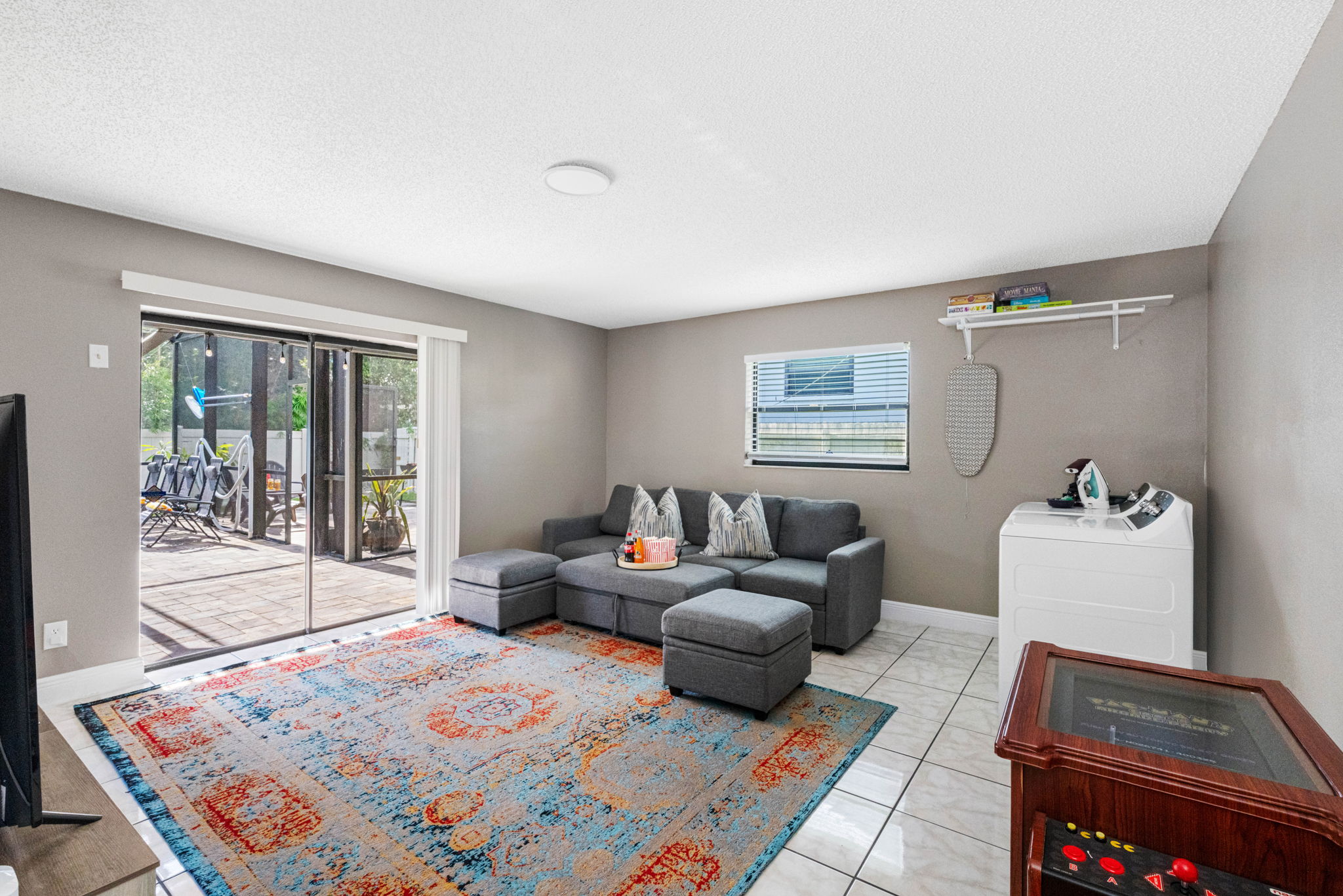 The room is bright and airy, thanks to a wide glass sliding door that leads directly to a screened patio—making indoor-outdoor living seamless.