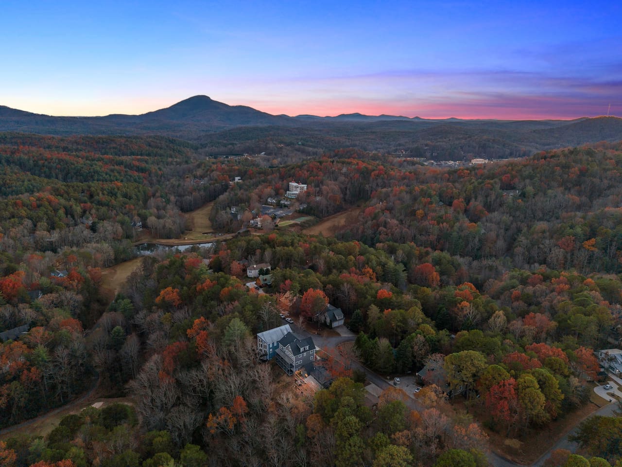 Twilight aerial view of the Helen property, with the mountains as a stunning backdrop—magical scenery from above.