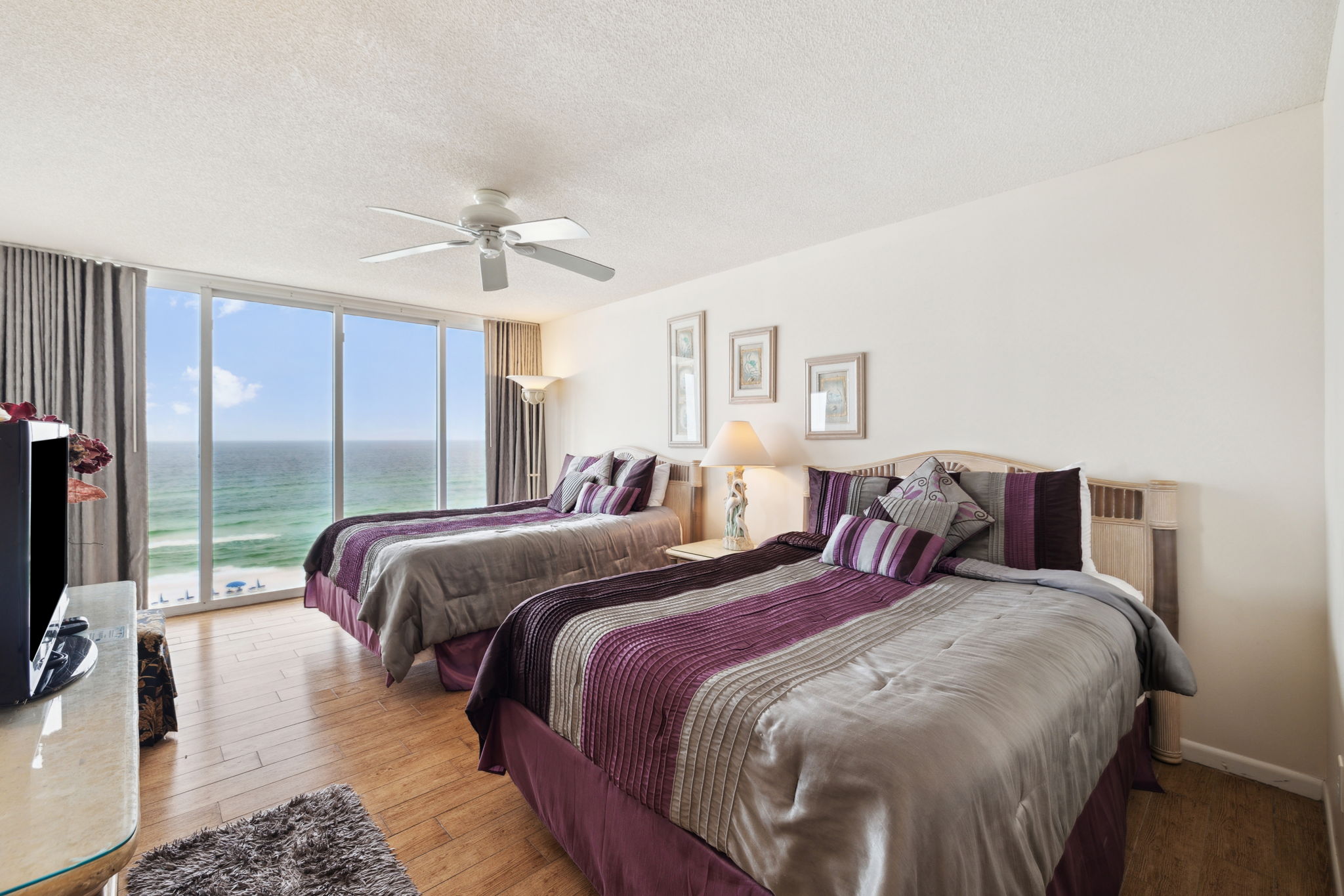 Double queen bedroom with floor to ceiling windows showcasing the beautiful Emerald Gulf waters and balcony access from bedroom
