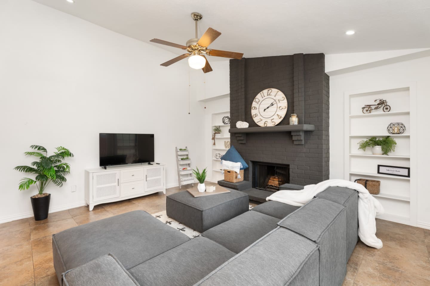 Spacious living area with fireplace, TV, and stylish shelving.