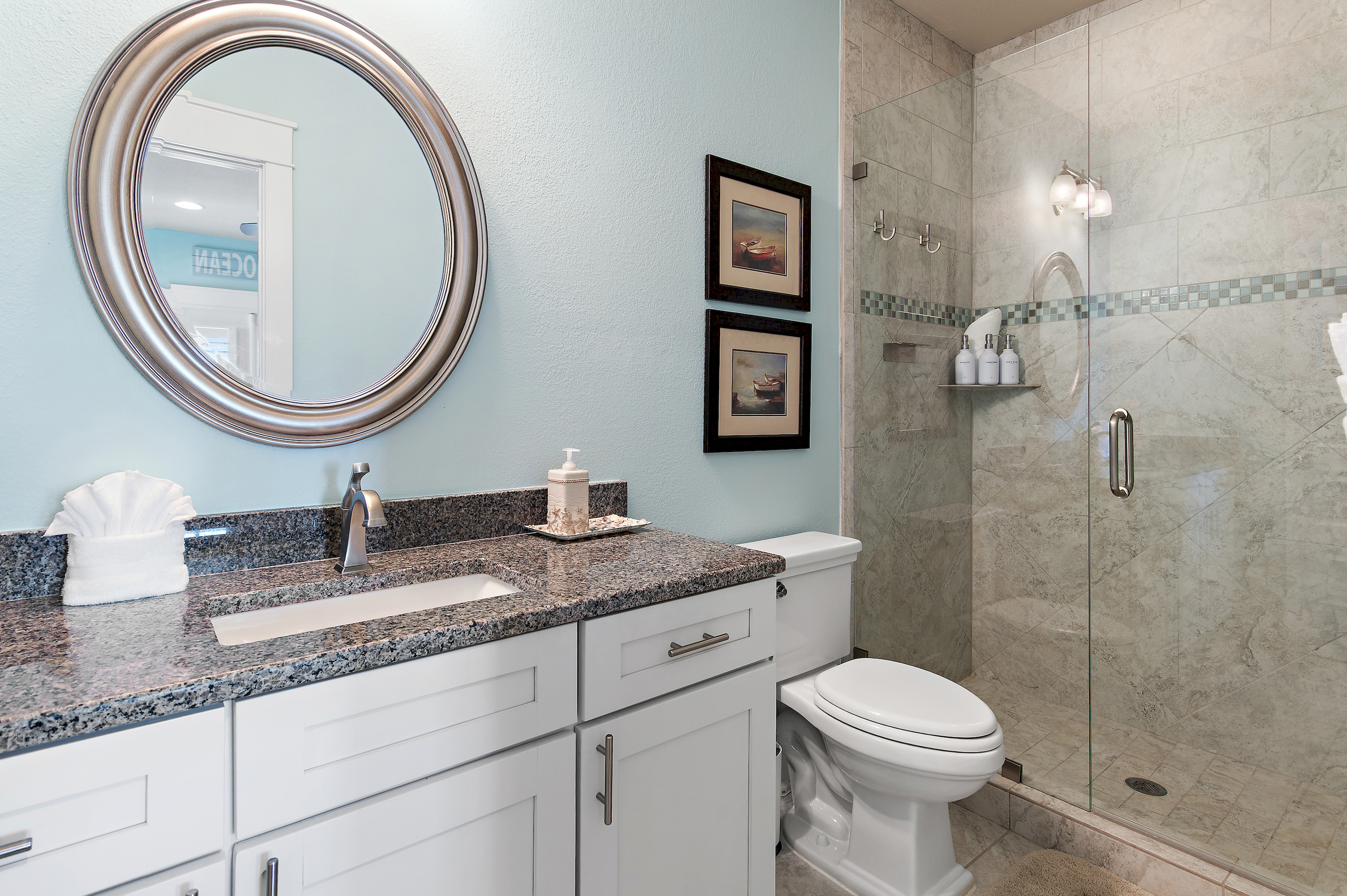 Bright, spacious bathroom with a walk in shower, generous vanity, and elegant coastal details.
