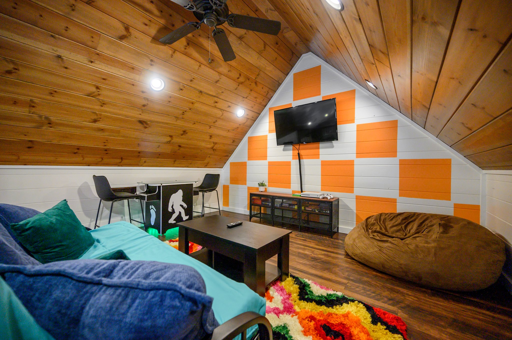 Disco Cowboy | Game loft with air hockey, Xbox and lounge seating. A twin daybed and trundle replaced the old futon; the cabin maximum remains 10 guests, with two king beds and six twin bunks as the advertised sleeping setup.