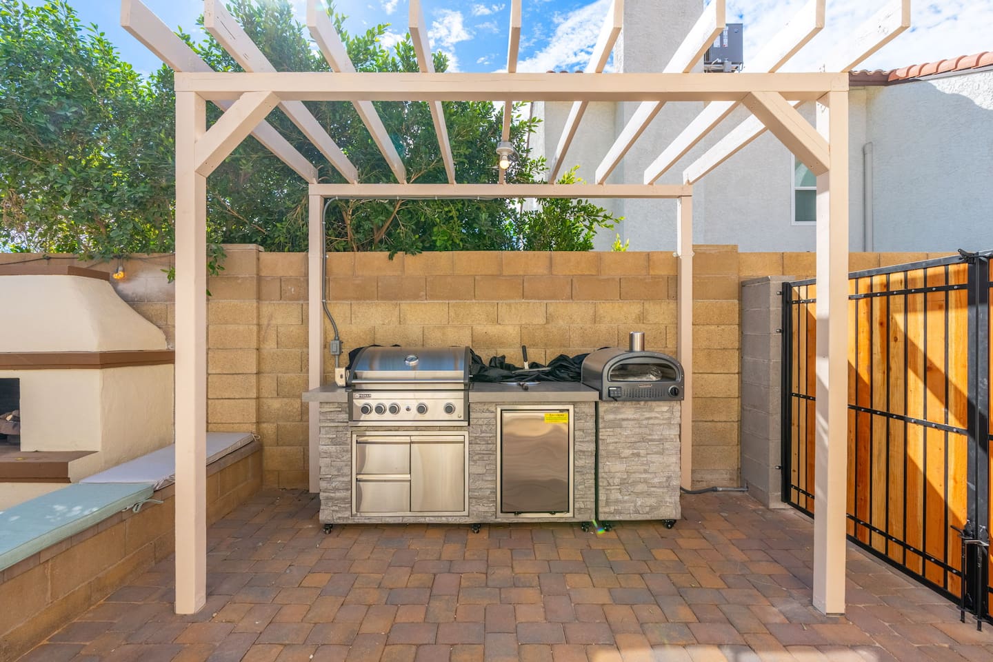 Outdoor kitchen with pergola, built-in grill, pizza oven, and stone finishes—fully equipped for chef-level outdoor cooking.