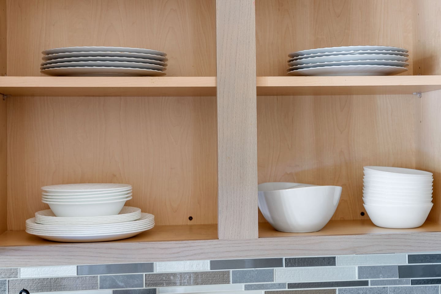 Enjoy the kitchen with neatly arranged open shelving, displaying a collection of elegant plates and bowls.