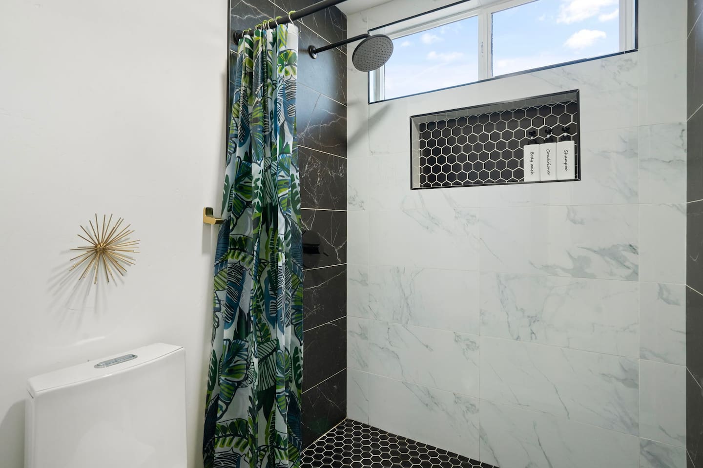 Bright bathroom with marble tile, walk-in shower, decorative accents, and modern fixtures.