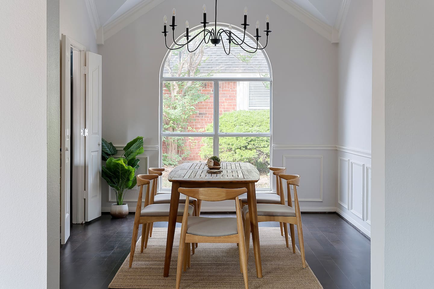 Enjoy a cozy dining area adorned with a wall mirror, inviting in the outdoor scenery through a window.