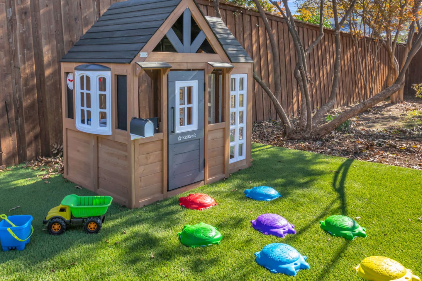 A charming backyard setup featuring a full play cottage and shaded play area—perfect for little adventurers who love outdoor time.