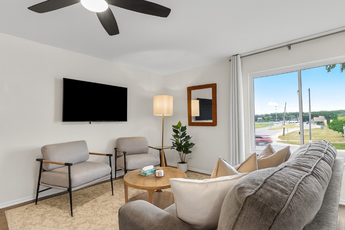 Bright living area with mounted Smart TV, cozy armchairs, and vibrant artwork to welcome you in.