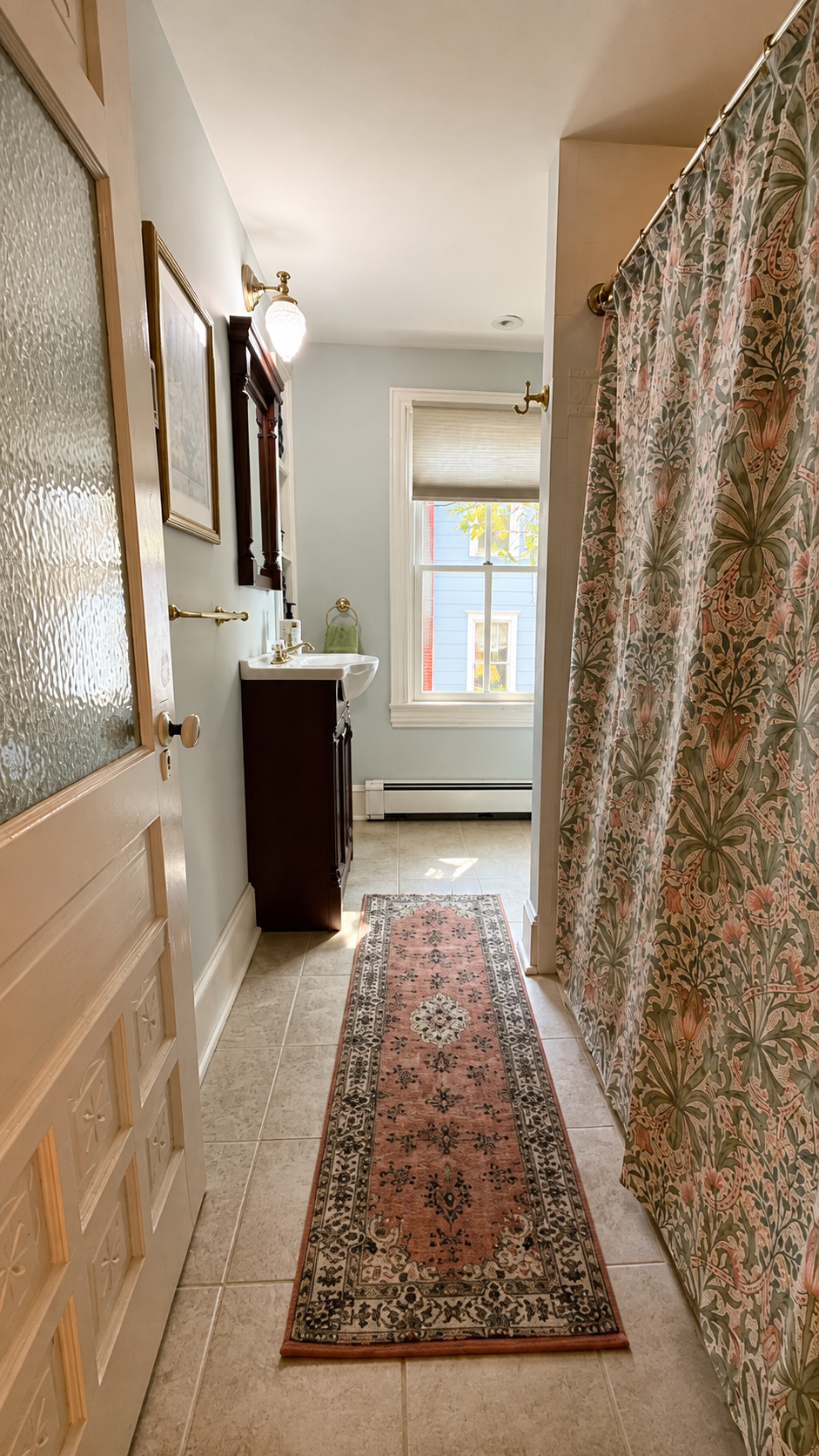 The full bath on the second floor — generous proportions, a Persian runner, and a shower curtain that holds its own in a house full of good taste.
