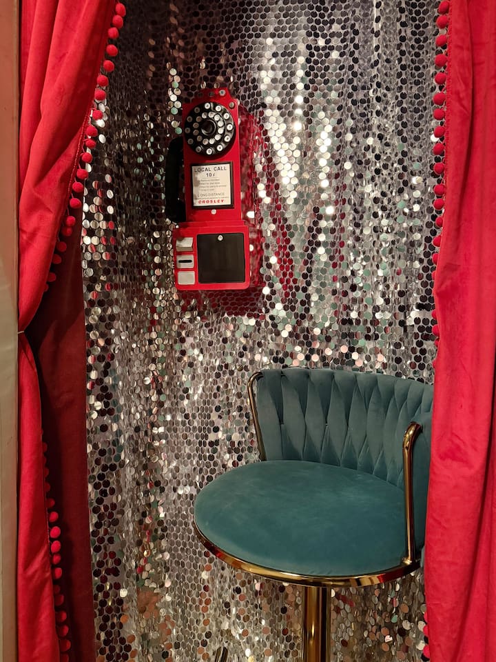 Hidden speakeasy photo booth with vintage rotary phone and glittering disco walls. One of  the most Instagrammable spots in this unique New Orleans Airbnb—perfect for girls trips,  bachelorettes, and celebration weekends. 