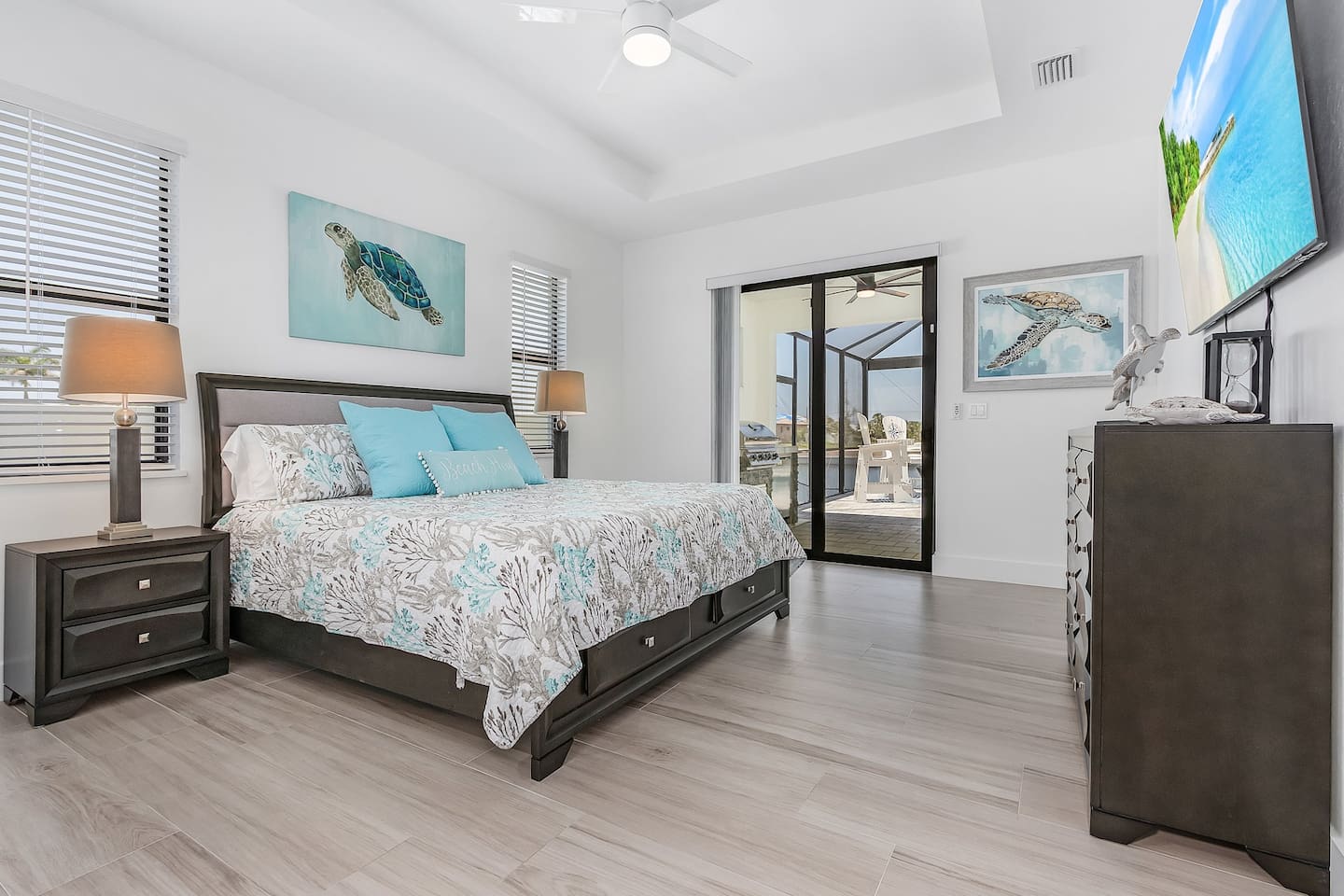 Stunning primary suite featuring a king-size bed, a TV, and direct access to the lanai and pool area!