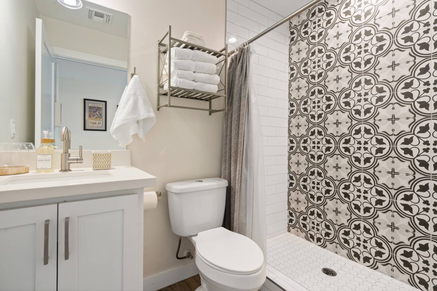 Ensuite bathroom with double sinks, tall storage cabinet, and a stylish walk-in shower. Backup towels are stored under vanity.
