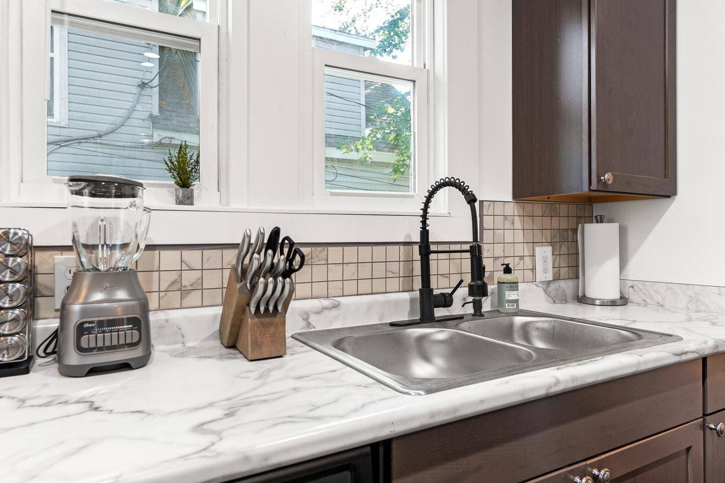 A sleek and fully equipped kitchen counter featuring a high-quality blender, an array of spices, sharp knives for all your culinary needs, and convenient paper towels. Perfect for whipping up your favorite recipes or enjoying a quick snack!