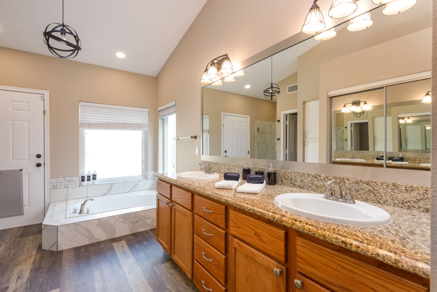 Primary ensuite vanity with double sinks, granite counter space, bright mirror lighting, and direct access from the bedroom.