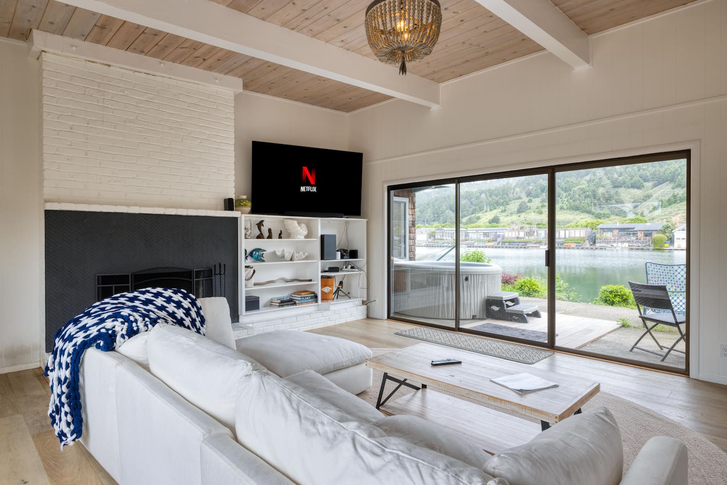 - Cozy living room with white sectional and sliding doors to the waterfront  
- Wall mounted TV with streaming access for entertainment anytime  
- Large windows flood the space with natural light and scenic views  
