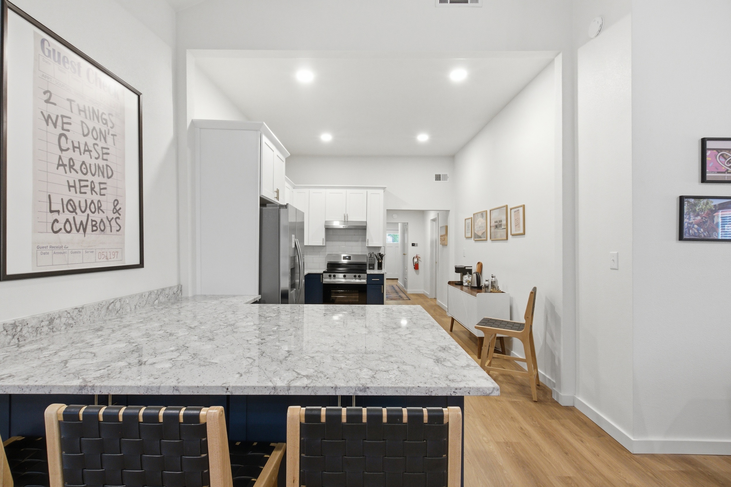 Open-concept kitchen with marble island and navy cabinetry. Fully stocked with cookware, dishes, wine glasses, and cooking basics. Near AT&T Stadium, Arlington TX.