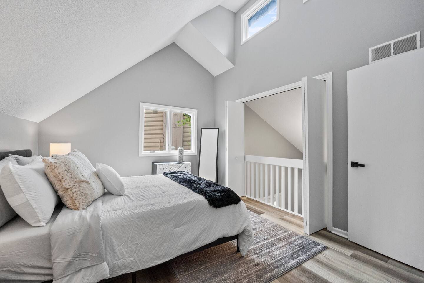 A well-lit view of the bedroom featuring a sleek mirror, adding depth and style to the space while enhancing the room's ambiance.