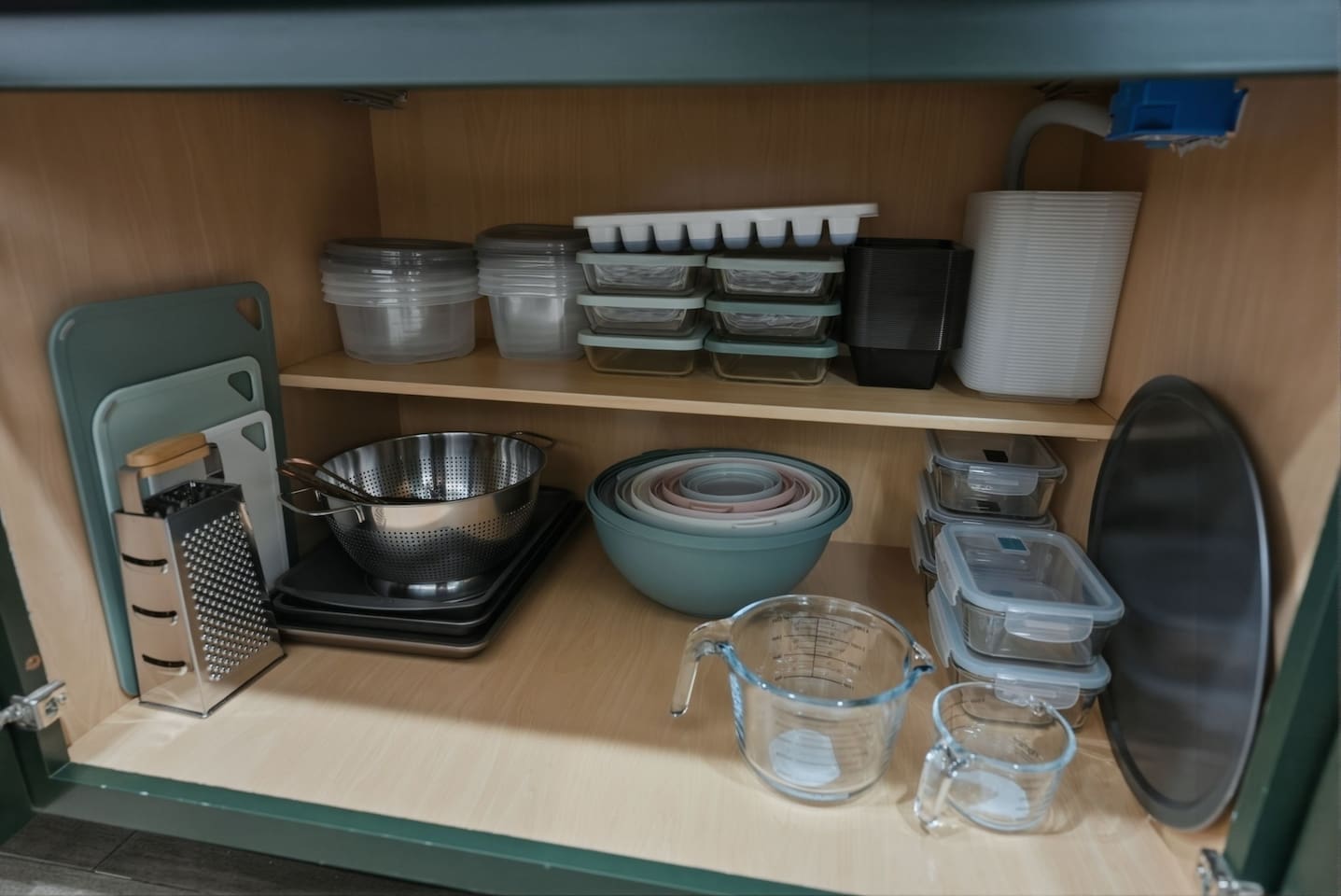 Well-organized kitchen storage with mixing bowls, measuring cups, cutting boards, and food containers for easy meal prep.