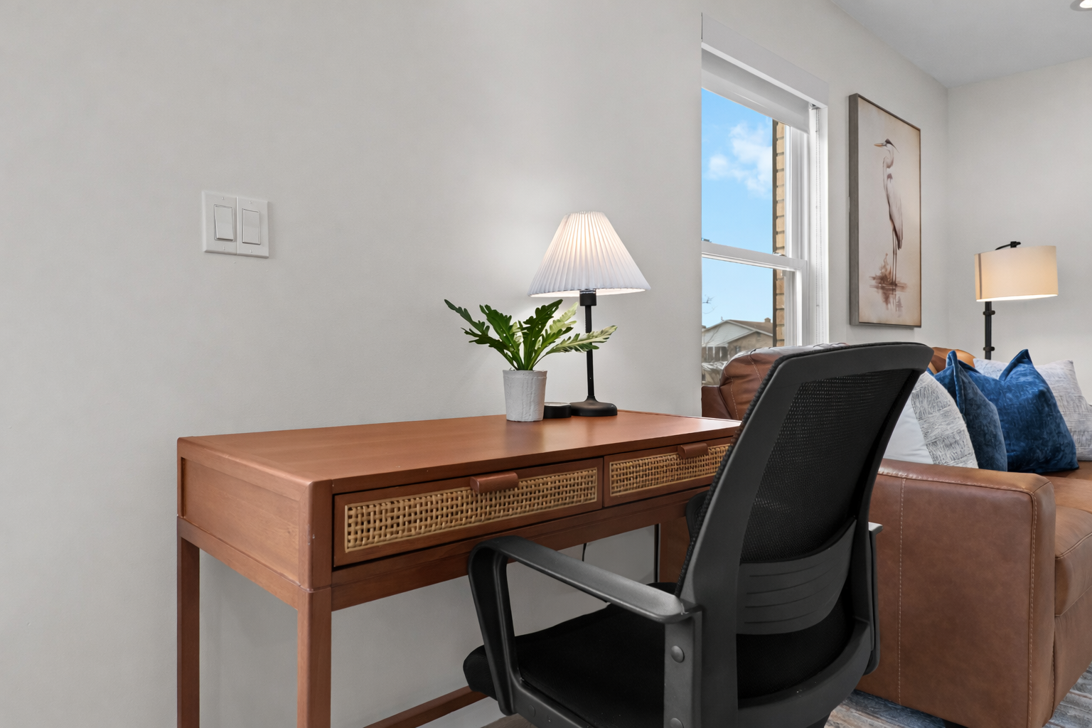 Sun-filled living room with a plush leather sofa, stylish décor, and calming artwork—an inviting spot to relax, recharge, and enjoy the natural light.