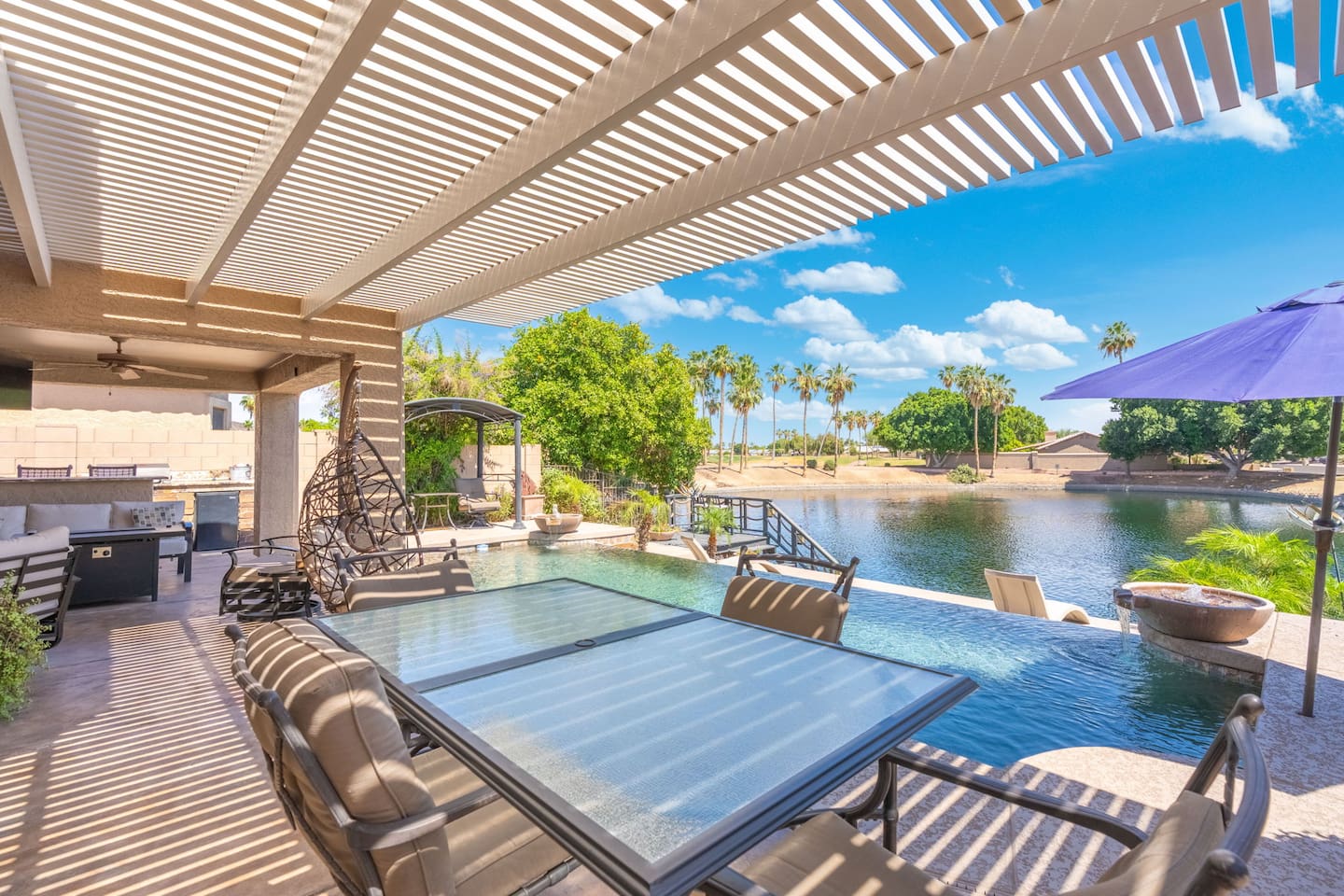 The pergola patio stretches out toward the pool and lake, offering the perfect blend of shade, breeze, and views — dine, lounge, or simply sit back and take it all in.