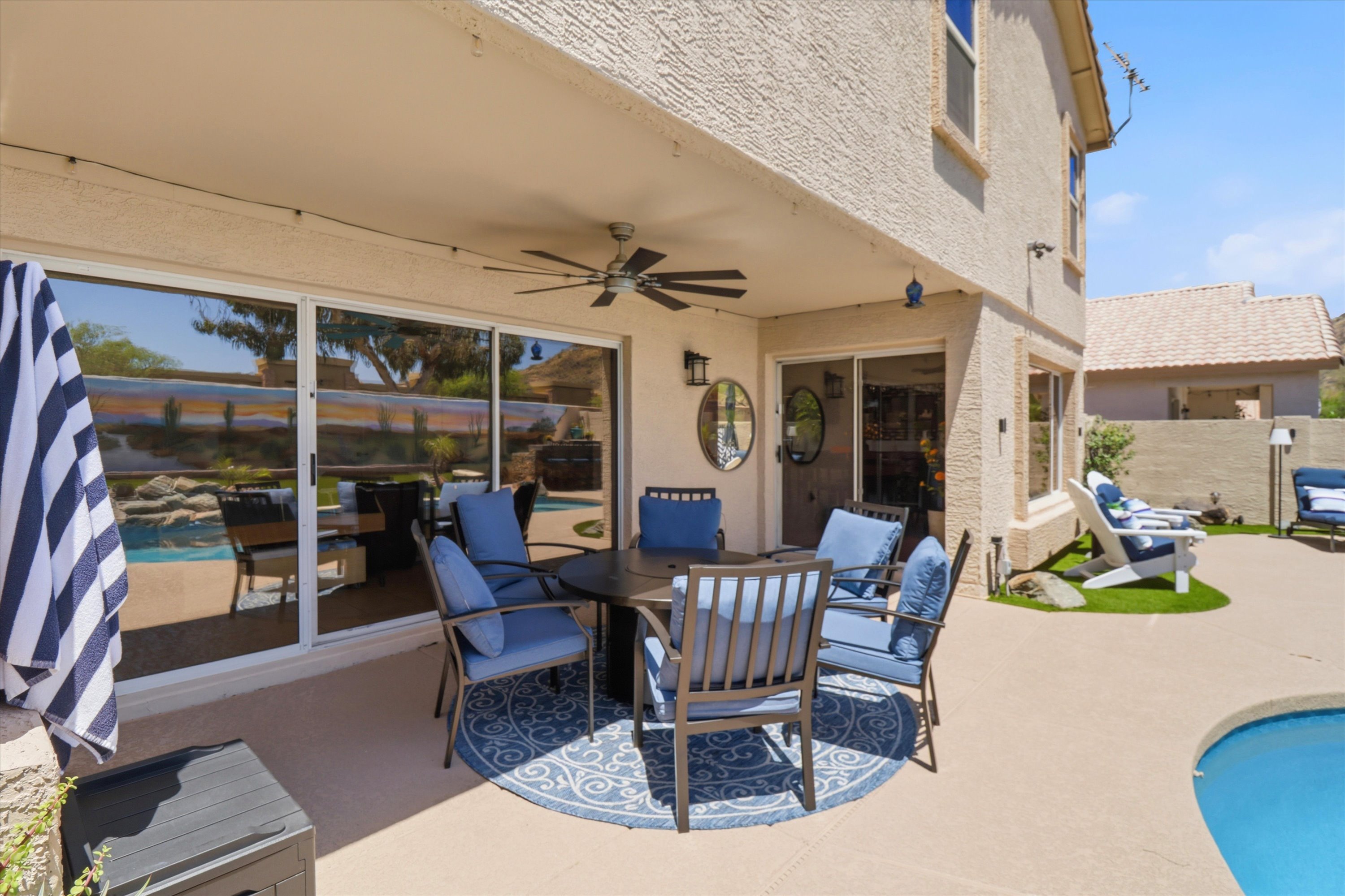 Covered patio seating with pool views, ceiling fan, and shaded space for outdoor meals or relaxed downtime.