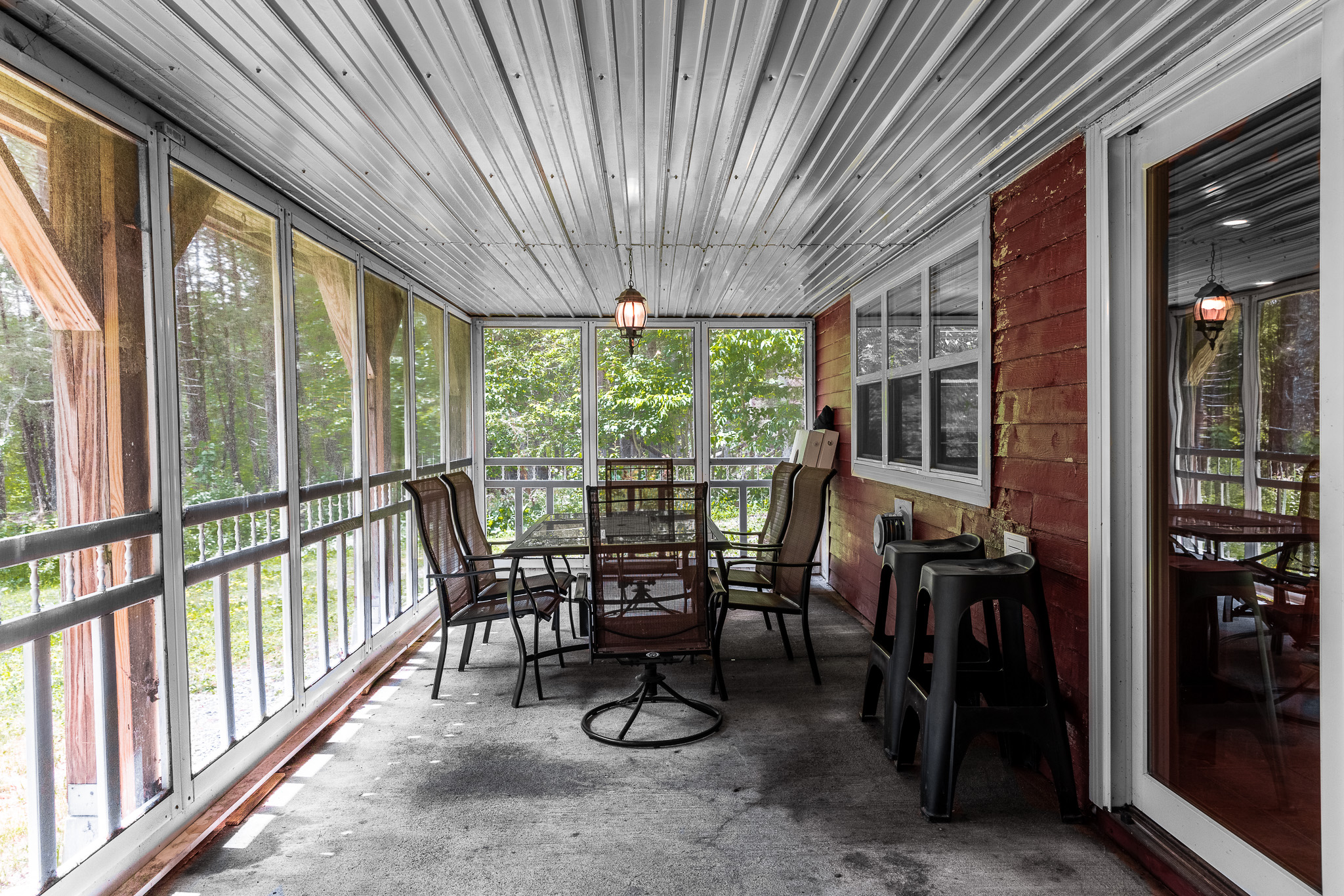 Screened and covered dining area under the deck with outdoor kitchen overlooking the lake. Also, corn hole boards.