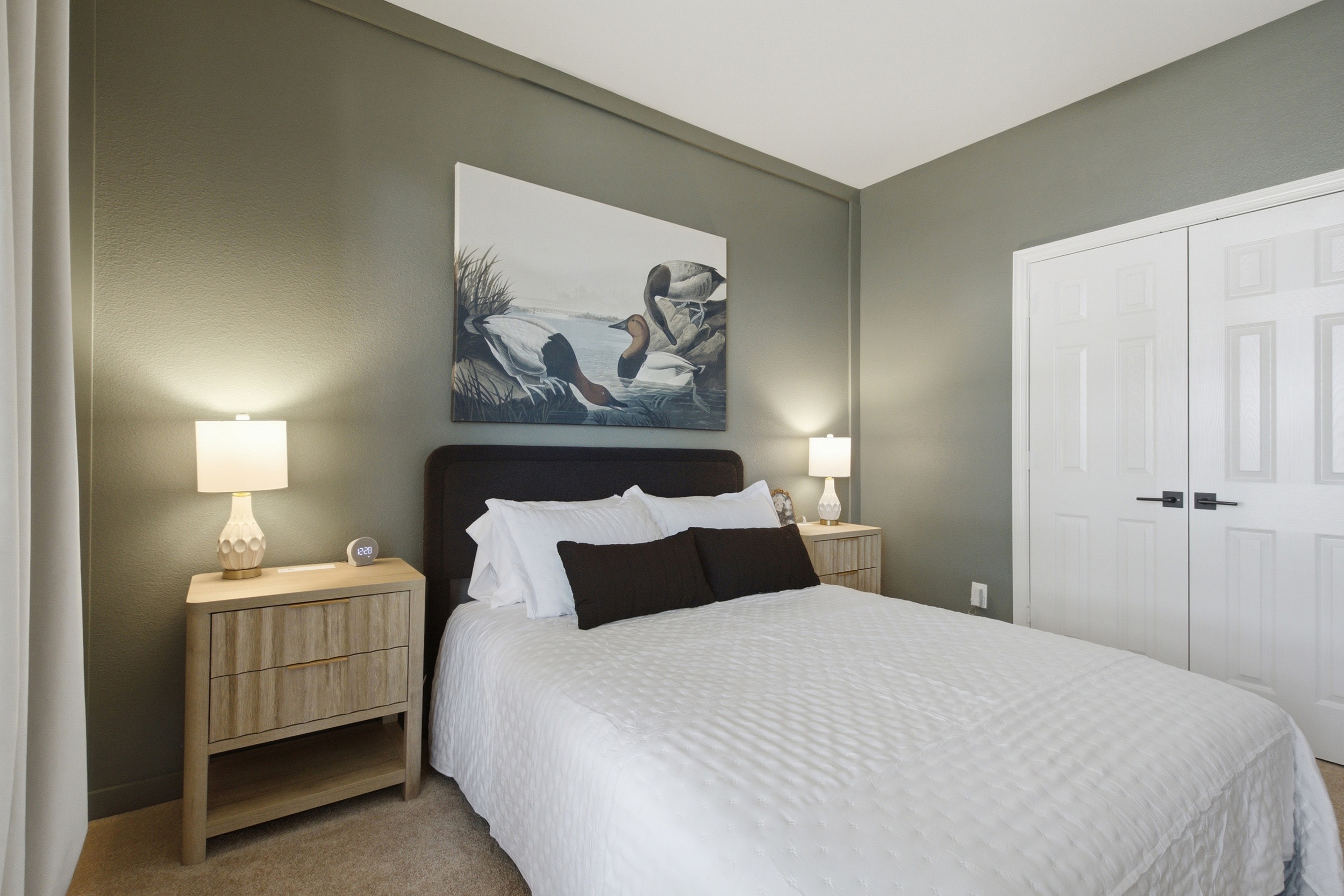 Guest Bedroom 2 with a Queen Bed, framed wall art, closet storage, and warm bedside lamps for a peaceful retreat after a day out.
