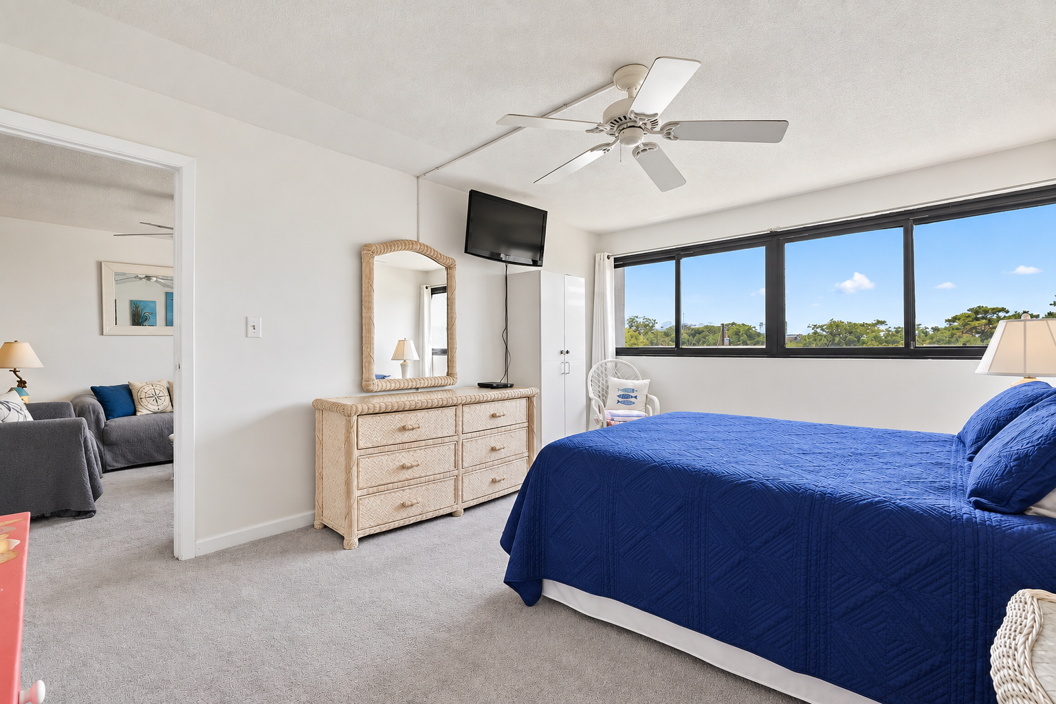 Queen bedroom with wide window views, wall-mounted TV, dresser storage, and direct access to the living room.