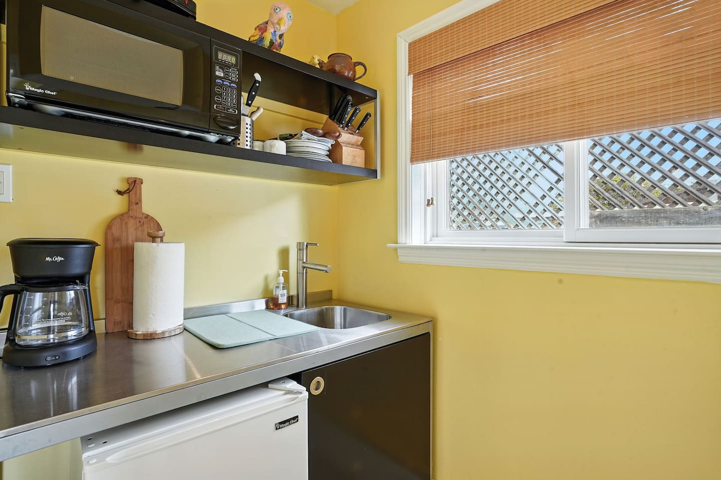 - Compact kitchenette with stainless steel sink, mini fridge, and microwave  
- Open shelving stocked with dishes, mugs, and cooking essentials for convenience  
- Ideal for preparing light meals or morning coffee before heading out  